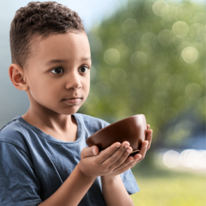 Young boy holding an empty bowl.