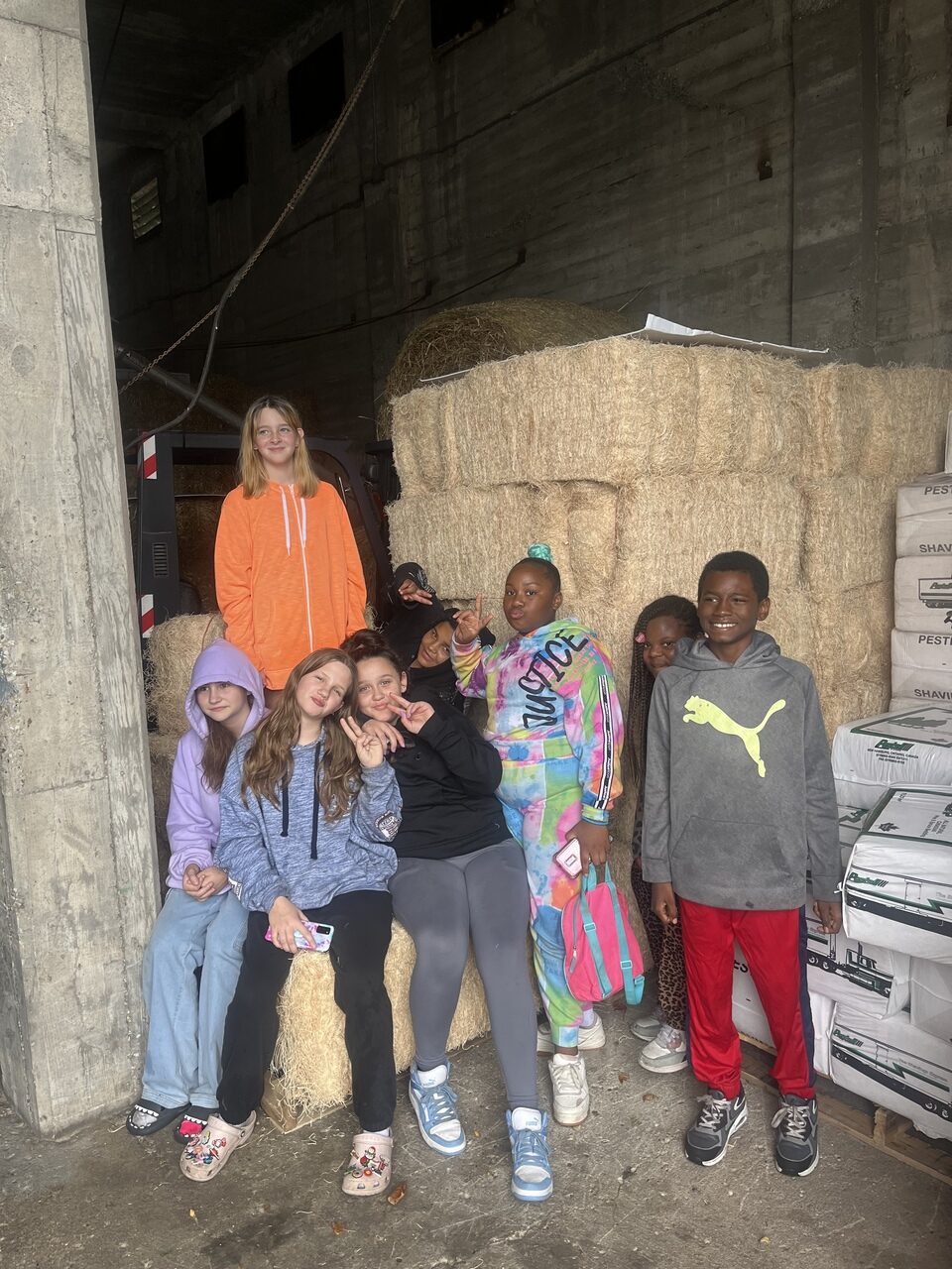 Seven students from Baldwin Junior High, standing in front of hay bales at the Detroit Zoo animal commissary