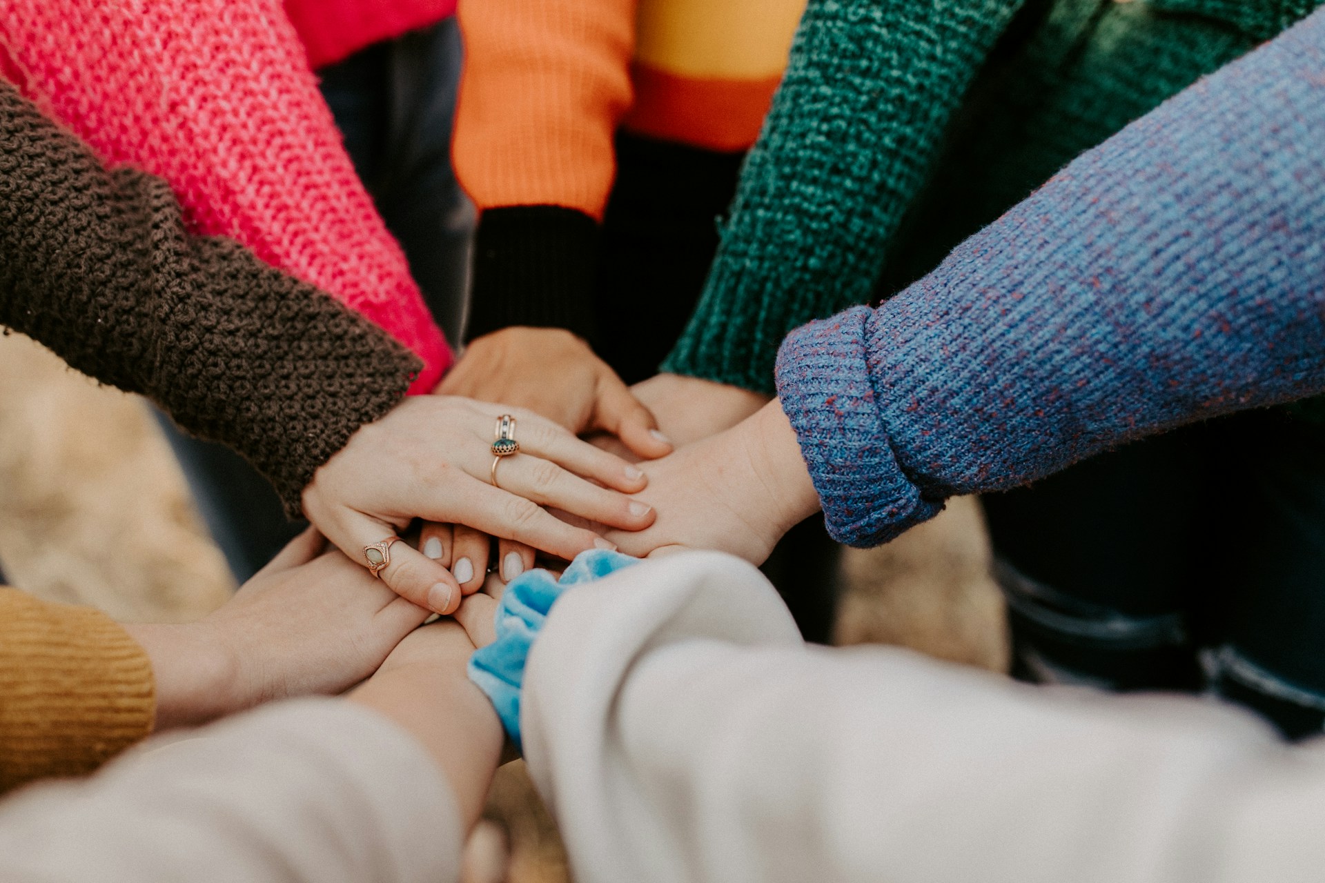 A group of people putting their hands together in a circle, representing social health.